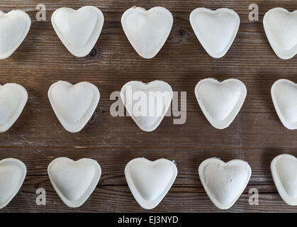 Roh-Ravioli in Form von Herzen auf eine Nahaufnahme von dunklem Holz. Ansicht von oben. Stockfoto