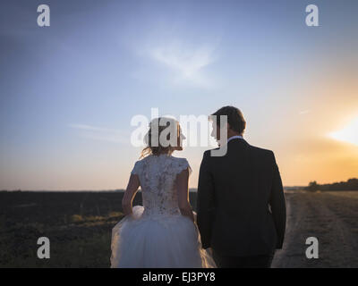 Junge Brautpaar reden auf dem Feld bei Sonnenuntergang. Brautpaar-b Stockfoto