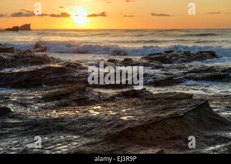 Die felsige Küste Playa Pelada sieht aus wie Wellen des Felsens, mit der Brandung stürzt bei Sonnenuntergang auf der Pazifikküste von Costa Rica. Stockfoto