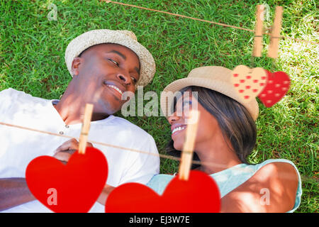 Zusammengesetztes Bild von glücklichen Paar im Garten zusammen auf der Wiese liegend Stockfoto