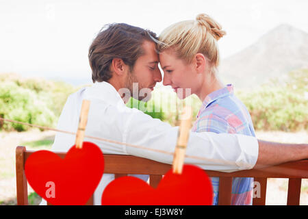 Zusammengesetztes Bild des süße paar sitzen auf Bank zusammen lächeln einander an Stockfoto
