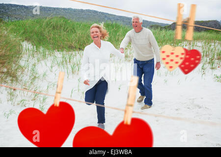 Zusammengesetztes Bild von fröhlich älteres Paar am Strand laufen Stockfoto