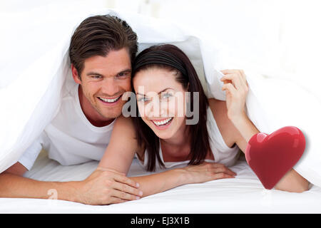 Zusammengesetztes Bild des glücklichen Paares auf Bett liegend Stockfoto