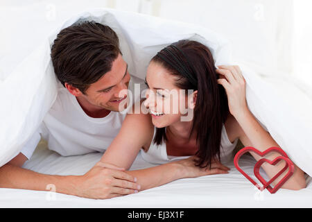 Zusammengesetztes Bild des Paares miteinander reden und auf Bett liegend Stockfoto