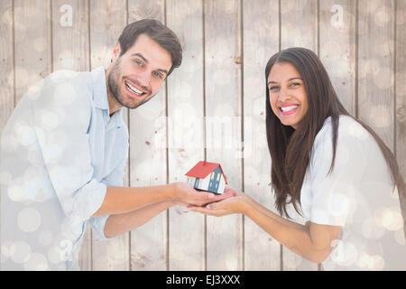 Zusammengesetztes Bild attraktives junges Paar halten eines Musterhauses Stockfoto