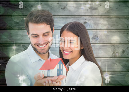 Zusammengesetztes Bild attraktives junges Paar halten eines Musterhauses Stockfoto
