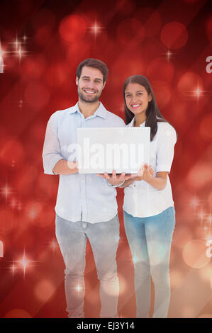 Zusammengesetztes Bild attraktives junges Paar hält ihren laptop Stockfoto