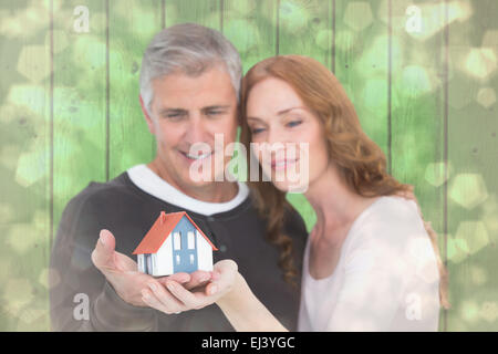 Zusammengesetztes Bild lässig Paares hält kleines Haus Stockfoto