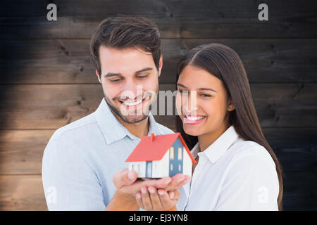 Zusammengesetztes Bild attraktives junges Paar halten eines Musterhauses Stockfoto