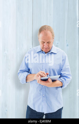 Zusammengesetztes Bild von reifer Mann mit seinem TabletPC Stockfoto