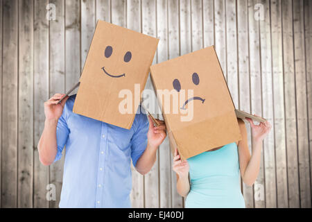 Zusammengesetztes Bild des Paares Bedrücktes Gesicht Boxen auf ihren Köpfen tragen Stockfoto