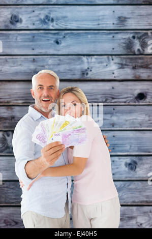 Zusammengesetztes Bild des glücklichen Paares blinkt ihr Geld Stockfoto