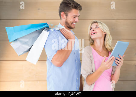 Zusammengesetztes Bild attraktives junges Paar halten Einkaufstaschen Blick auf TabletPC Stockfoto