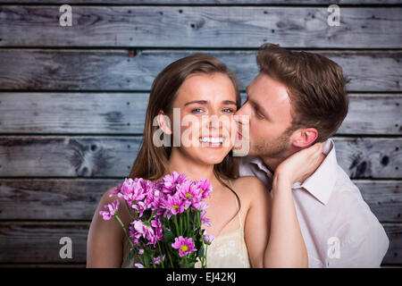 Zusammengesetztes Bild des Mannes, die Frau zu küssen, wie sie Blumen hält Stockfoto