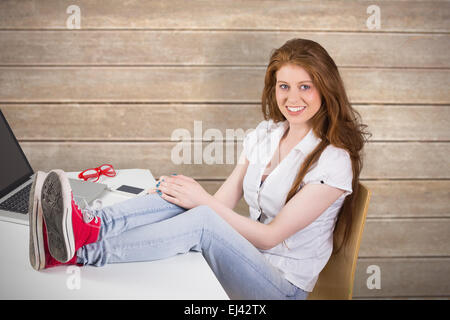Zusammengesetztes Bild hübsche rothaarige mit Füße hoch auf Schreibtisch Stockfoto