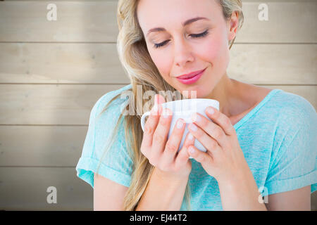 Zusammengesetztes Bild der lächelnde Blondine mit heißen Getränk entspannen Stockfoto