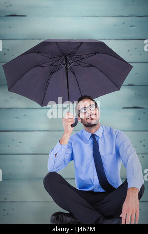 Zusammengesetztes Bild der Geschäftsfrau im Anzug sitzen Regenschirm mit gedrückter Stockfoto
