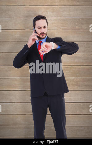 Zusammengesetztes Bild des ernsthaften Geschäftsmann überprüfen der Zeit während auf dem Handy Stockfoto