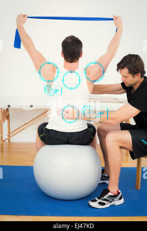 Zusammengesetztes Bild des Menschen auf Yoga-Ball mit einem Physiotherapeuten arbeiten Stockfoto