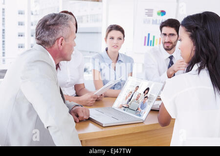 Zusammengesetztes Bild glücklich Geschäftsleute versammelt um einen Blick in die Kamera laptop Stockfoto