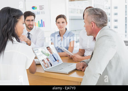 Zusammengesetztes Bild von fröhlich Geschäftsmann posieren, während seine Kollegen arbeiten Stockfoto