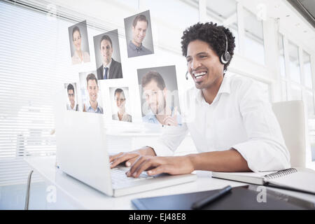 Zusammengesetztes Bild des glücklichen Geschäftsmann arbeitet an seinem Schreibtisch tragen Kopfhörer Stockfoto