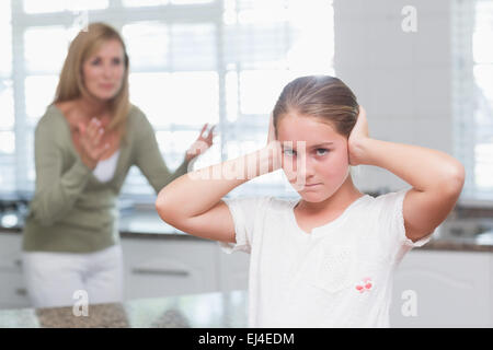 Aufgeregt Mädchen für ihre Ohren während ihre Mutter schreien Stockfoto