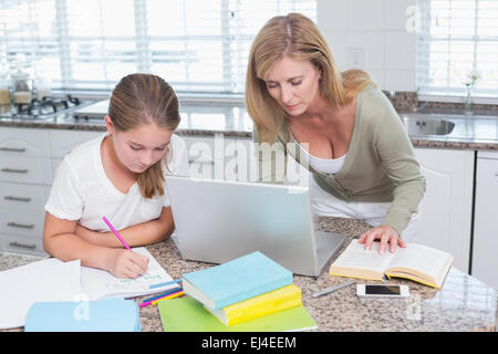 Mutter mit Laptop während Tochter Hausaufgaben Stockfoto