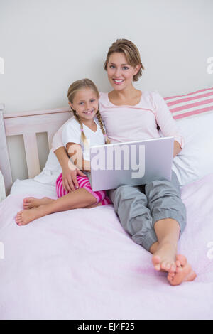 Mutter und Tochter mit Laptop im Bett Stockfoto