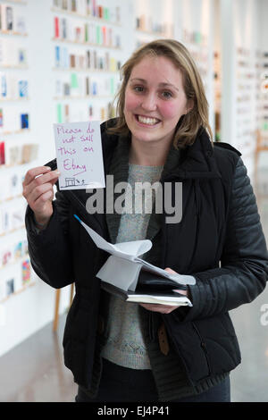 London, UK. 21. März 2015. Im Bild: Jessica Milligan, die ganze Nacht in der Warteschlange hatte, hält das Kunstwerk "Bitte nicht das bei Ebay von Jeremy Deller verkaufen". Viele Kunstliebhaber in der Warteschlange an der Royal College of Art Dyson Builing durch die Nacht, erster in der Linie für den Stewarts Recht RCA Geheimnis Postkarte Vertrieb sein die heute beginnt. RCA-Geheimnis ist eine jährliche Spendenaktion der Postkarte Größe Arworks um Geld für die RCA Fine Art Student Award Fund. In diesem Jahr 3.000 angezeigt Kunstwerke, darunter Arbeiten von berühmten Künstlern wie Bob & Roberta Smith, Paula Rego und Nick Park - die sind anonym - ar Stockfoto