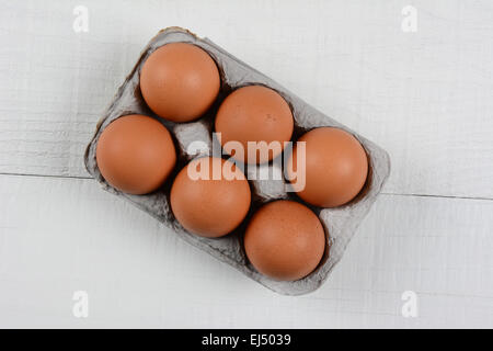 Hohen Winkel Schuss ein six-Pack von organischen Brown Eiern auf einem rustikalen weißer Holztisch. Querformat mit Textfreiraum. Stockfoto