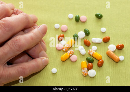 Hände einer älteren Frau mit ihr Medikamente liegen verstreut auf dem Tisch vor ihr mit Sortiment von Tabletten, Capsuls. Stockfoto