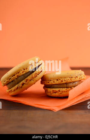 Karamell Makronen auf orange und dunkles Holz Tischdekoration. Stockfoto