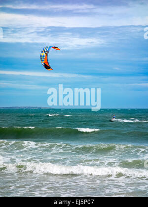 Ein Kiteboarder wird von einem Power Kite vor dem Mui Ne Strand über das Wasser gezogen. Mui Ne, Provinz Binh Thuan, Vietnam. Stockfoto