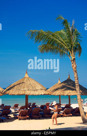 Palme und strohgedeckten Sonnenschirmen und Liegestühlen am Strand von Vinpearl Resort. Insel Phu Quoc, Provinz Kien Giang, Vietnam. Stockfoto