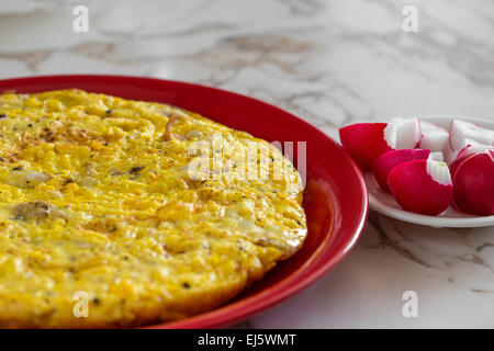 Omelett mit Käse und Radieschen auf einer roten Platte Stockfoto