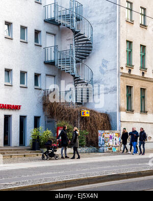 Mehrfamilienhäuser, attraktive Feuerleiter Wendeltreppe und Passanten in Berliner Straße Stockfoto