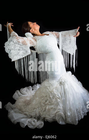 Flamenco-Tänzerin in weiß gekleidet mit Ausdruck des Gefühls leidenschaftlich in schwarzem Hintergrund Stockfoto