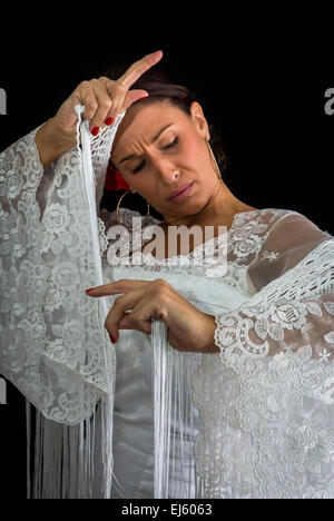 Flamenco-Tänzerin in weiß gekleidet mit Ausdruck des Gefühls leidenschaftlich in schwarzem Hintergrund Stockfoto