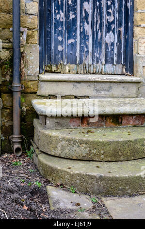 Eine alte Tür mit interessanten Peeling Paint Textur und alte Schritte. In Bakewell, England. Stockfoto