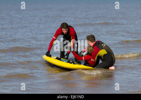 Freiwillige Rettungsschwimmer von RNLI üben bei Flut Rettungstraining und -Genesung auf dem Land auf Ainsdale, Merseyside, Strand. Surf Lifesaving ist ein Sport, der Leben retten kann und aus verschiedenen Rennen besteht – Schwimmen, Boardpaddeln und Skikaddeln. Simulierte Rettungen werden verwendet, um das Reagieren unter verschiedenen Bedingungen zu üben. Stockfoto