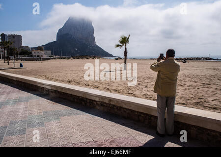 Ein Tourist nimmt ein Foto von der Naturstein-Wahrzeichen in Calpe, Spanien. Stockfoto