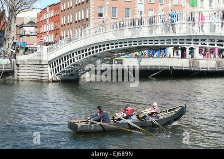 Menschen-Zeile in einem Currach unter der Ha'Penny-Brücke über den Fluss Liffey im Stadtzentrum von Dublin am ersten Tag des Frühlings Stockfoto