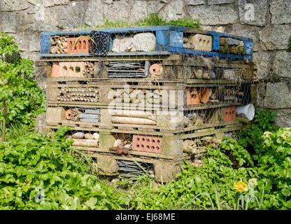 Ungezieferhotel. Ein Stapel alter Paletten, gefüllt mit Ziegeln, Holzschiefern und anderen Gegenständen, um Insekten wie einsame Bienen und Käfer anzulocken Stockfoto