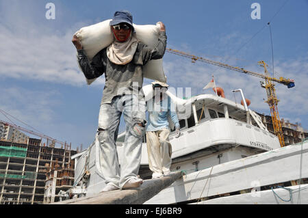 Indonesische Abourers entladen Mehlsäcke aus dem Schiff in den Hafen Sunda Kelapa in Jakarta, Indonesien. Die Schiffe kommen aus vielen Regionen von Indonesien wie Sumatra, Borneo (Kalimantan) und Sulawesi, und sie tragen landwirtschaftliche Erzeugnisse nach Jakarta. Als Phinisi Schiffe zurück in ihre Heimat gehen, tragen sie Baustoffe wie Stahl, Zement usw.. Stockfoto