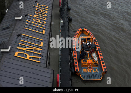 Eine neue RNLI-Rettungsboot festgemacht, in der Themse-warum ein Crew-Mitglied arbeitet daran, es Schiff bereit. Stockfoto