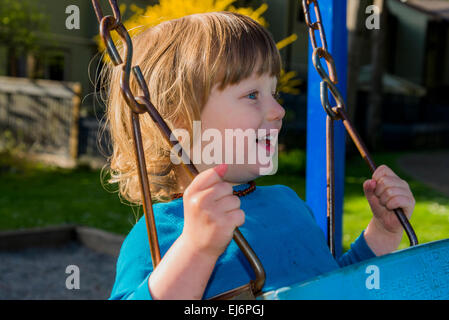 Fröhlicher Junge auf Schaukel. Stockfoto