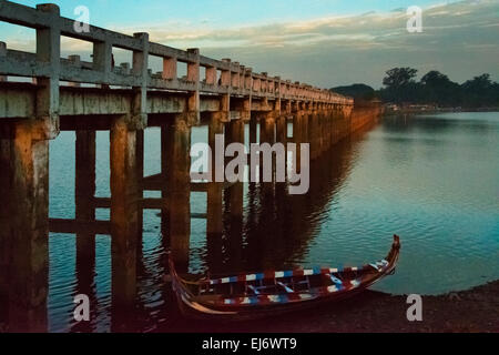 Kanu mit Amarapuras berühmten Teak U Bein Brücke auf Taungthaman See im Morgengrauen, Mandalay, Myanmar Stockfoto