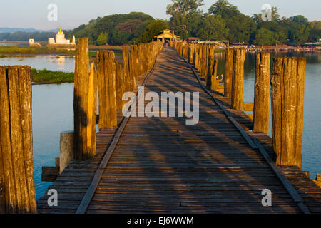 Teakholz U Bein Brücke mit Zitadelle Pagode in der Ferne auf Taungthaman-See bei Sonnenaufgang, Amarapura, Mandalay, Myanmar Stockfoto