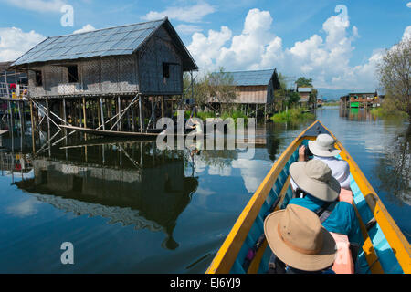 Touristenboot vorbei Stelzenläufer Hütten der schwimmenden Dorf am Inle-See, Shan State in Myanmar Stockfoto